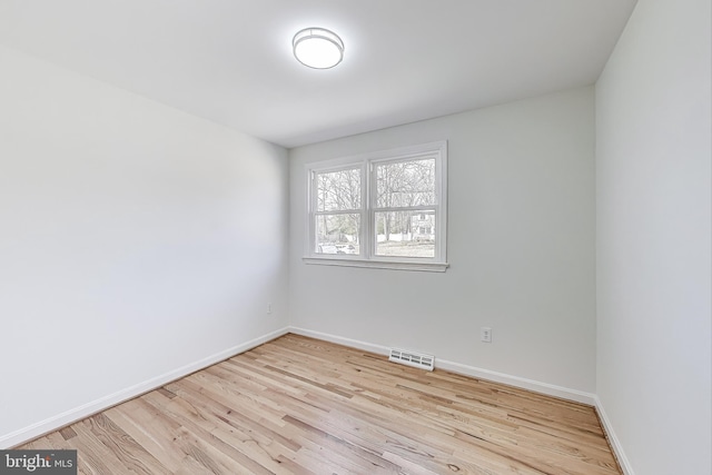 spare room with visible vents, baseboards, and wood finished floors