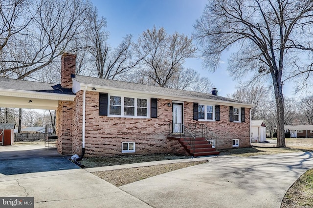 ranch-style home featuring a chimney, concrete driveway, brick siding, and a carport