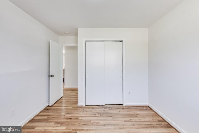 unfurnished bedroom with a closet, baseboards, and light wood finished floors