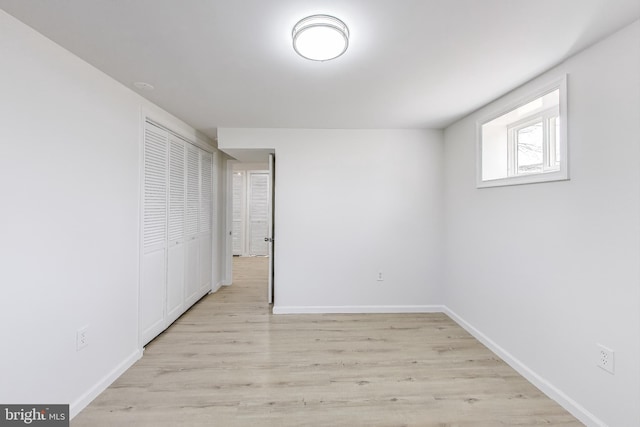 unfurnished bedroom with a closet, light wood-type flooring, and baseboards