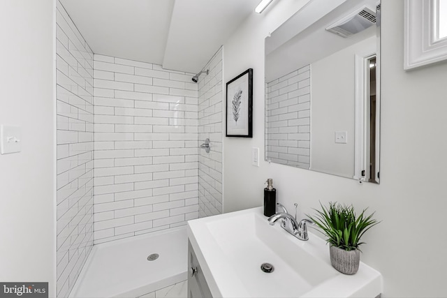 bathroom with vanity, visible vents, and tiled shower