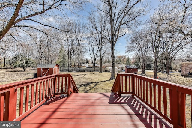 wooden deck featuring an outbuilding, a storage shed, and fence