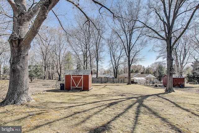 view of yard featuring an outbuilding, a storage unit, and fence