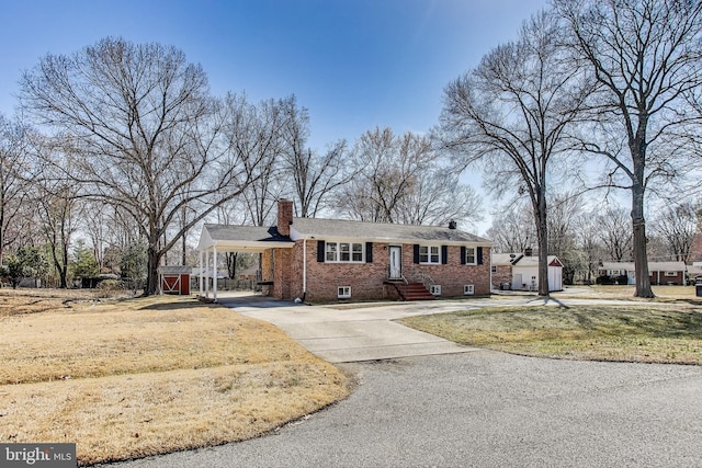 ranch-style house featuring brick siding, a chimney, aphalt driveway, and an outbuilding