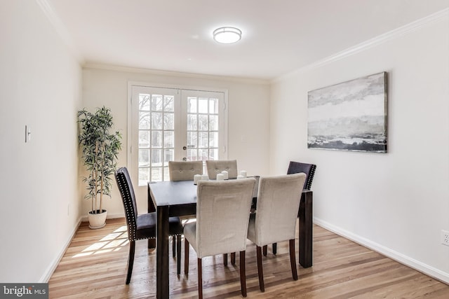 dining space featuring crown molding, wood finished floors, baseboards, and french doors