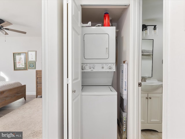 washroom featuring ceiling fan, stacked washer / drying machine, and sink