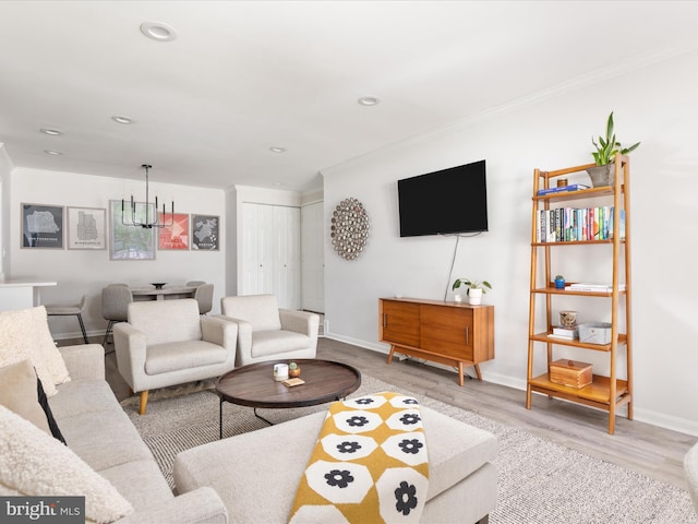 living room featuring a notable chandelier, crown molding, and light hardwood / wood-style floors