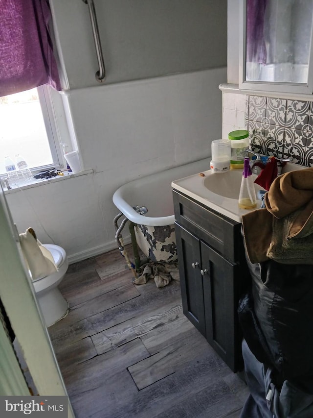 bathroom with a tub to relax in, vanity, toilet, and hardwood / wood-style floors