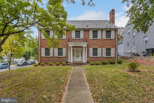 colonial inspired home featuring a front lawn