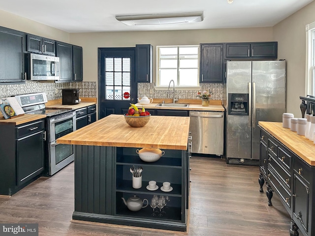 kitchen featuring a center island, appliances with stainless steel finishes, butcher block counters, and sink