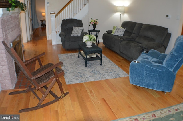 living room with a brick fireplace and hardwood / wood-style flooring