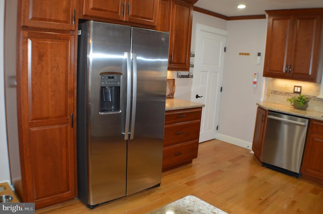 kitchen with tasteful backsplash, light stone counters, light hardwood / wood-style floors, stainless steel appliances, and crown molding