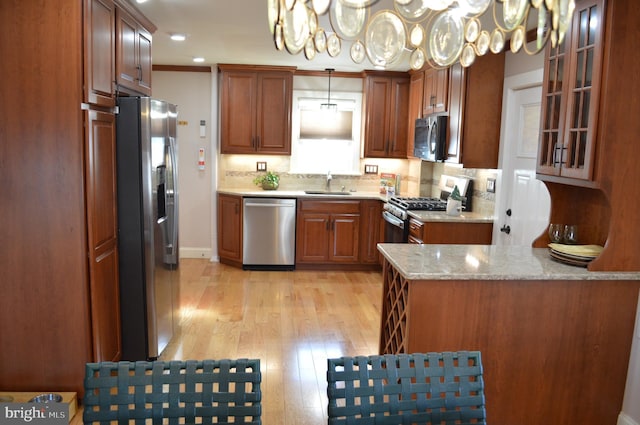 kitchen featuring decorative light fixtures, sink, decorative backsplash, stainless steel appliances, and light wood-type flooring