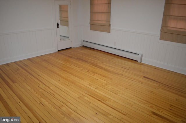 unfurnished room with light hardwood / wood-style floors, built in features, and a baseboard heating unit