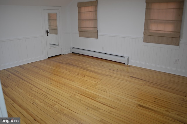 unfurnished room with a baseboard radiator and light wood-type flooring