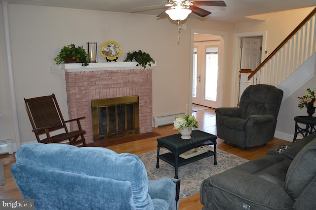 living room with ceiling fan, a brick fireplace, light hardwood / wood-style flooring, and a baseboard heating unit