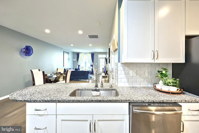 kitchen featuring light stone counters, dishwasher, sink, and white cabinets