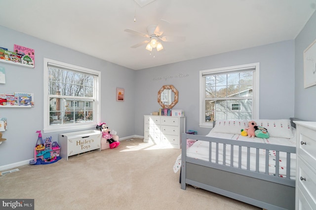 bedroom featuring multiple windows, light colored carpet, and ceiling fan