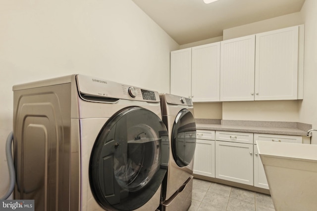 laundry area featuring cabinets, washer and dryer, and light tile patterned flooring