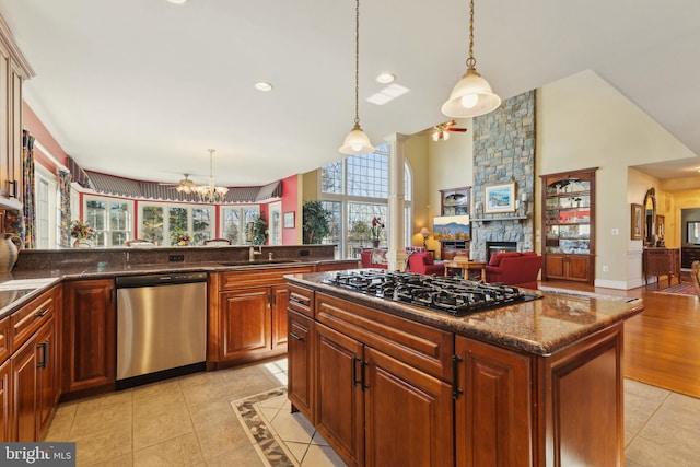 kitchen with a stone fireplace, sink, decorative light fixtures, light tile patterned floors, and appliances with stainless steel finishes