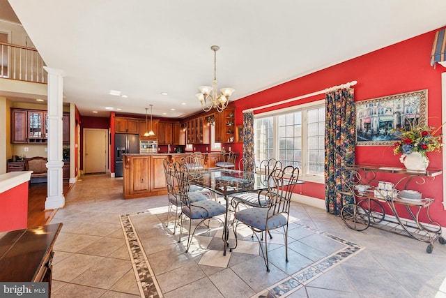 dining room with a chandelier, decorative columns, and light tile patterned floors