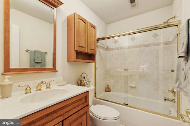 full bathroom featuring vanity, shower / bath combination with glass door, and toilet