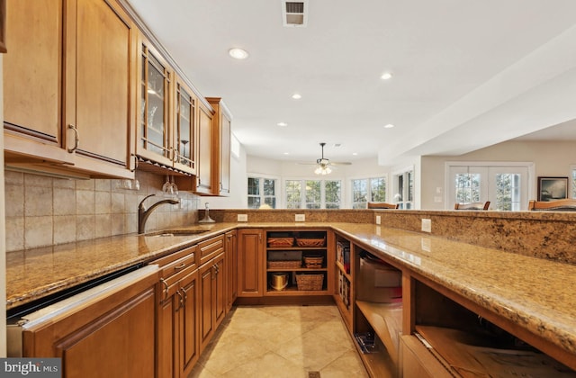 kitchen featuring tasteful backsplash, light stone countertops, sink, and light tile patterned floors