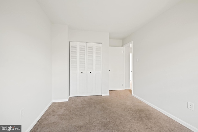 unfurnished bedroom featuring light carpet and a closet