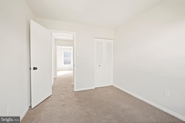 unfurnished bedroom with light colored carpet and a closet