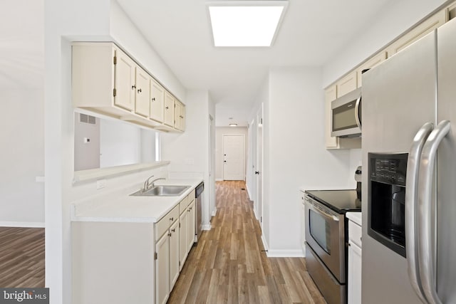 kitchen featuring stainless steel appliances, sink, and light wood-type flooring