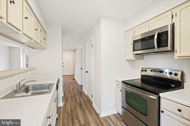 kitchen with stainless steel appliances, sink, dark hardwood / wood-style floors, and cream cabinetry