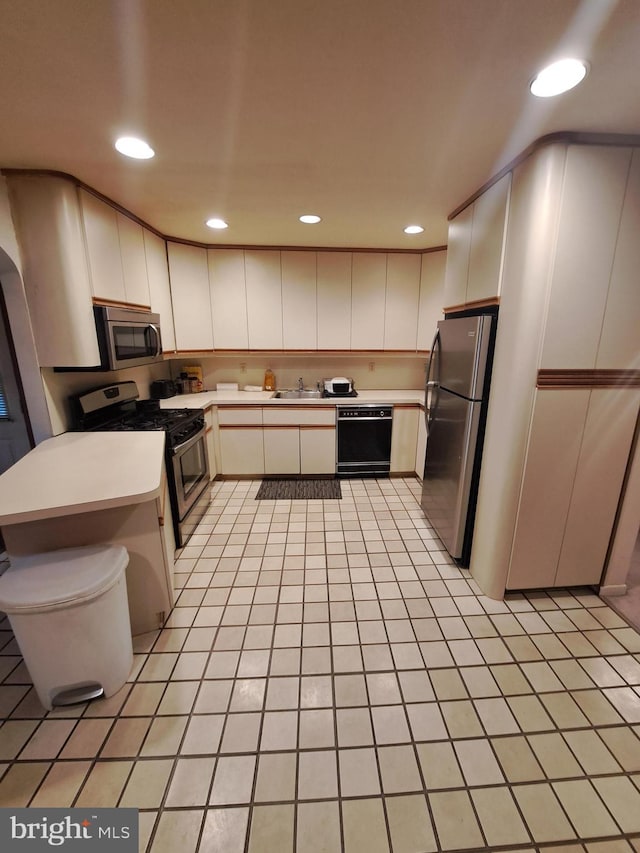 kitchen with white cabinetry, sink, light tile patterned floors, and stainless steel appliances