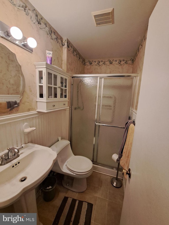 bathroom with sink, toilet, an enclosed shower, and tile patterned flooring