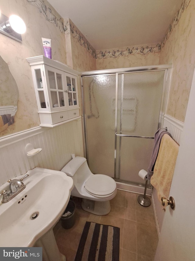 bathroom with tile patterned flooring, sink, an enclosed shower, and toilet