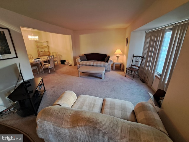 carpeted living room featuring a notable chandelier