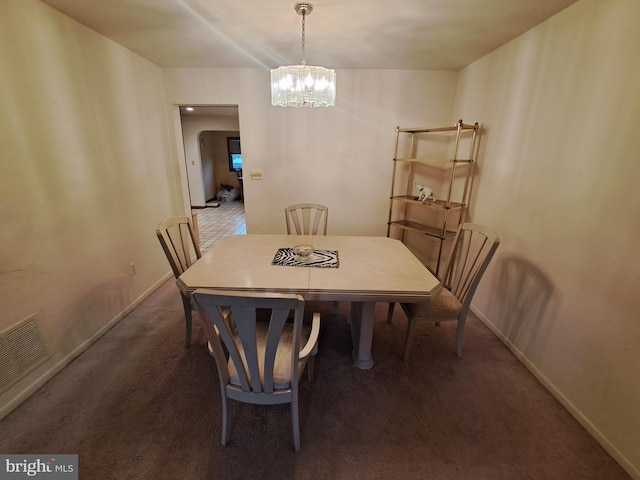 carpeted dining space with a chandelier