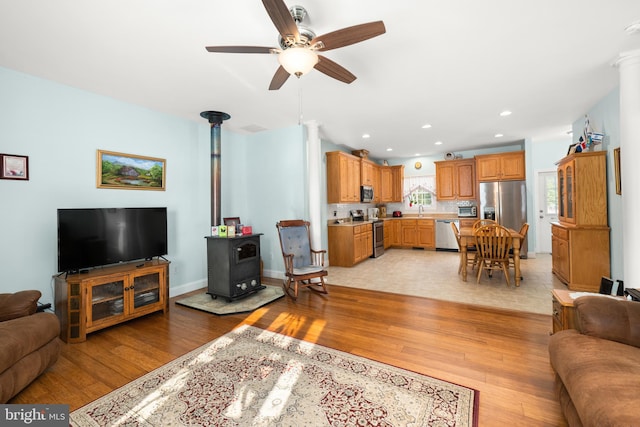 living room with ceiling fan, light hardwood / wood-style floors, and a wood stove