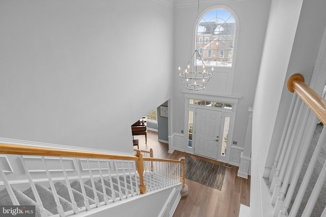 entryway with hardwood / wood-style flooring, plenty of natural light, a high ceiling, and a notable chandelier