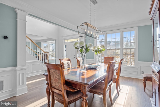 dining space featuring ornate columns, ornamental molding, a healthy amount of sunlight, and light hardwood / wood-style floors