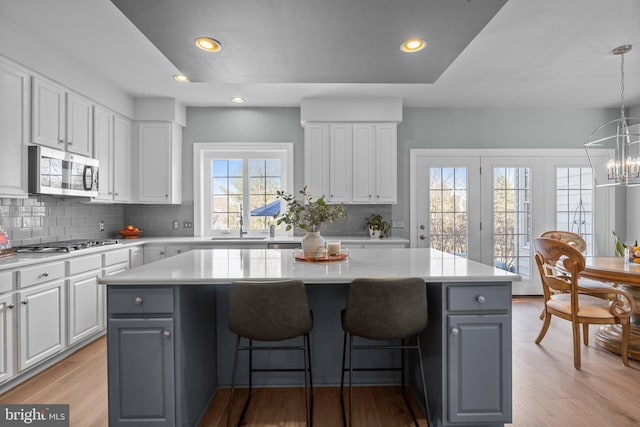 kitchen featuring appliances with stainless steel finishes, decorative light fixtures, a kitchen island, and white cabinets