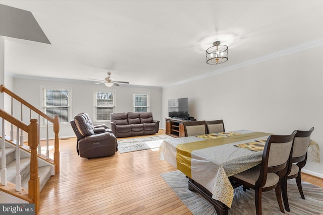 dining space with ornamental molding, ceiling fan with notable chandelier, and light wood-type flooring