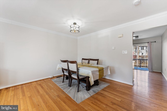 dining space with hardwood / wood-style flooring, crown molding, and an inviting chandelier