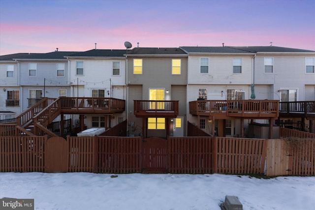 snow covered rear of property with a deck