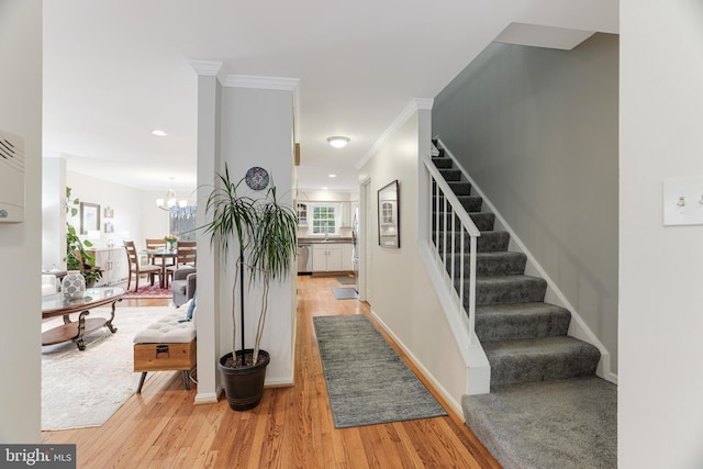 staircase with an inviting chandelier, crown molding, and wood-type flooring