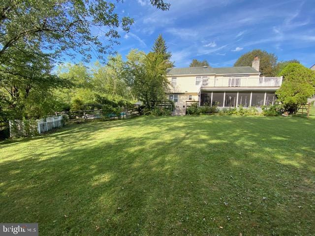 view of yard featuring a sunroom and a balcony