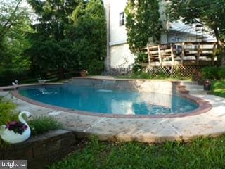 view of swimming pool with a wooden deck and a diving board