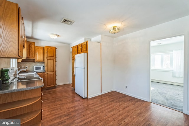 kitchen with dark hardwood / wood-style floors, a baseboard radiator, sink, decorative backsplash, and white appliances