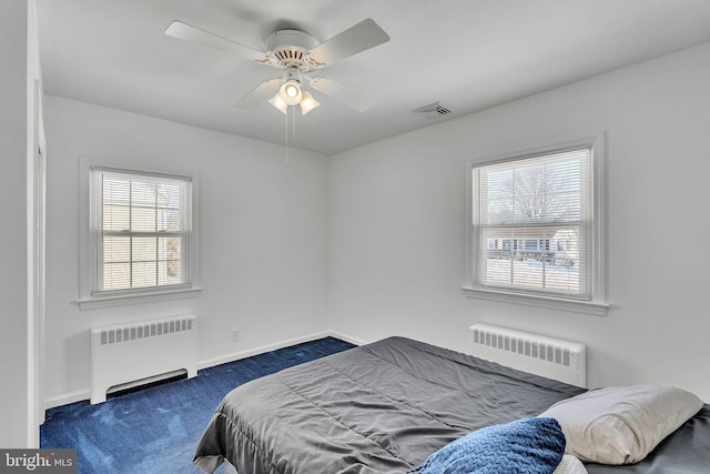 bedroom with multiple windows, radiator, and ceiling fan