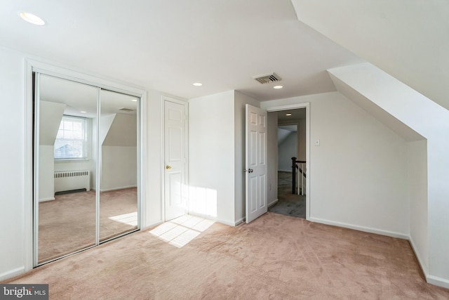 additional living space with light colored carpet, radiator, and vaulted ceiling