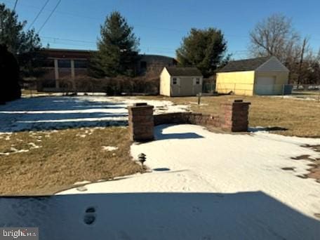 yard layered in snow featuring a shed